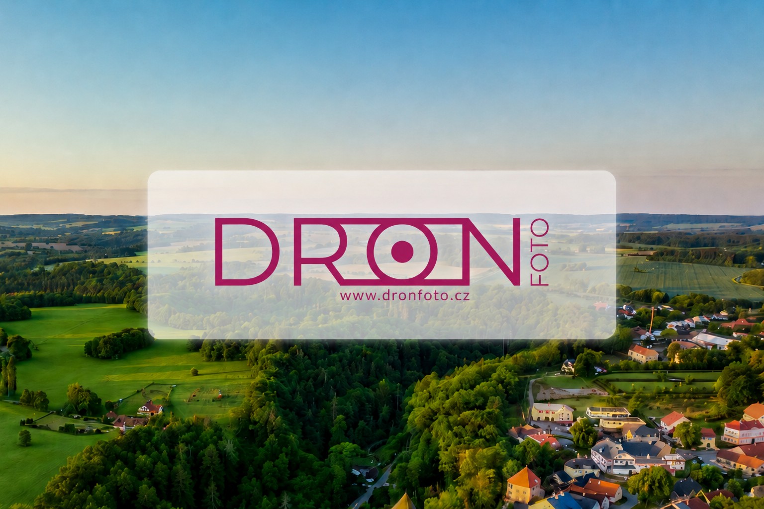 Letecký pohled na krajinu s vesnicí, přes ni průhledný banner s logem DRONFOTO.cz.