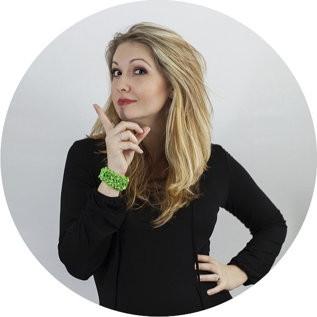 Simona Andrejsová. Blond žena v černém sako, prsty u brady, jedna ruka v bok, neutrální pozadí.